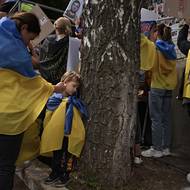 Ukrajinská žena chlácholí svého malého syna uprostřed davu, který čeká na návrat ukrajinských vojáků z ruského zajetí. 25. května 2025.