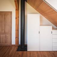 Kouřovod krbu ukazuje, že i v moderní dřevostavbě se vyplatí mít záložní zdroj tepla. Dřevo dokáže během chvíle vyhřát celý interiér a snížit spotřebu elektřiny.