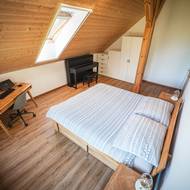 „Nechtěli jsme, aby některý pokoj zůstal nevyužitý,“ vysvětlují majitelé. Proto ložnici v podkroví doplnili o pracovní stůl i piano a vznikl univerzální rodinný prostor.