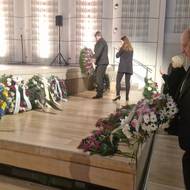 Smuteční hosté pokládají věnce a květiny.