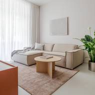 Obývací zónu definují koberec a rohová hygge pohovka v neutrálních barvách.