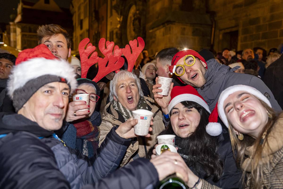 Lidé vítají příchod nového roku na zaplněném Staroměstském náměstí.