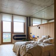 Přiznané betonové stropy a topení v industriálním stylu jsou v záměrném kontrastu k jemným dřevěným povrchům a bytovému textilu z přírodních materiálů.