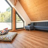 Podkroví slouží jako odpočinková zóna s velkou rohovou sedačkou a výhledem do přírody. Velká šikmá okna propouštějí spoustu světla a propojují interiér s okolím.