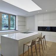 Kuchyň je zařízená v bílé barvě, architekti ji doplnili prvky v přírodní barvě dřeva a spotřebiči v černém provedení.