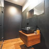 V přízemí se nachází jedna ze dvou koupelen. Za posuvnými černými dveřmi je navržená vana a také je tam umístěná jednotka tepelného čerpadla.