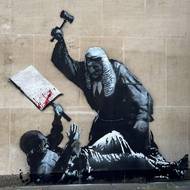 Jedno z nejnovějších kontroverzních děl. V září 2025 Banksy na budovu Královského soudního dvora v Londýně namaloval výjev bránícího se muže se zakrvácenou cedulí, nad kterým se sklání soudce připravený k úderu. 