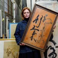 Ester Geislerová při rozhovoru k výstavě v DOX. V ruce má kaligrafii, kterou její táta dělal na dřevo emailem a tuší.