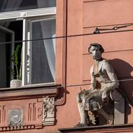 Činžovní domy se na Palmovce stavěly od přelomu 19. a 20. století, proto mají často i sochařskou výzdobu. Této konkrétní soše zřejmě zůstal doplněk z doby covidu. 