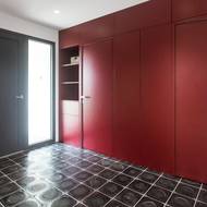 V předsíni je položena tmavá čedičová dlažba a červená stěna s integrovanými úložnými prostory. Vše je v jedné rovině.