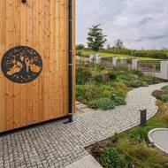 Dřevěný ornament znázorňuje Budhu sedícího pod domem.