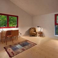 Interiér i exteriér stavby zpestřují jasně červené rámy oken.