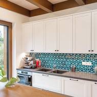 Keramický obklad za pracovní plochou v kuchyni je připomínkou tyrkysové barvy vstupních dveří i hexagonální dlažby za nimi.