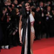 Demi Moore ve slonovinových šatech kopírujících její štíhlou postavu pózuje fotografům.